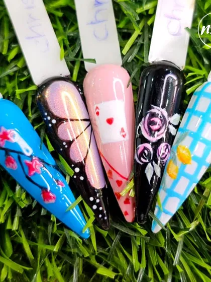 A vibrant collection of hand-painted nail art by students, featuring butterflies, playing cards, and floral patterns. This shows the range of their artistic skills.