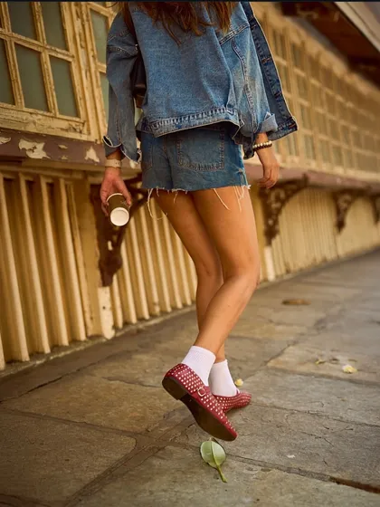 Walking through the city in our red studded ballet flats. This image captures the movement and energy of the shoe, a perfect companion for a day out and about.