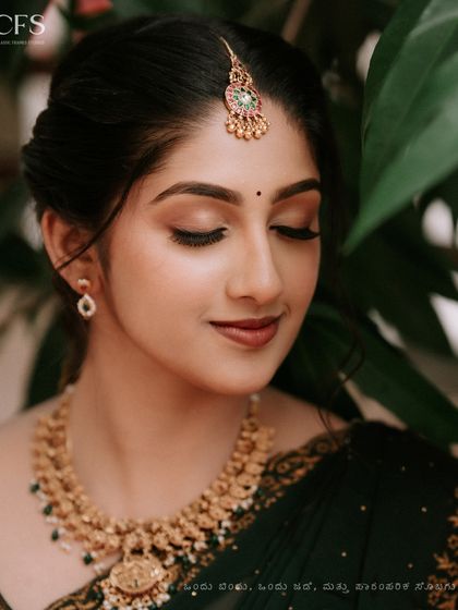 A stunning close-up of a bride, showcasing her flawless makeup and traditional gold jewelry. This portrait captures the grace and elegance of a South Indian bride on her engagement day.