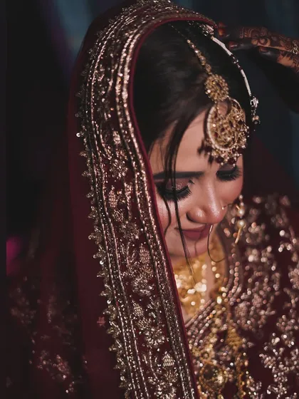 A close-up shot capturing the emotion of the day. The focus is on her expressive eyes, enhanced with soft smokey makeup, and the intricate details of her maang tikka.