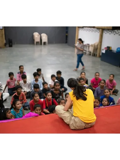 A quiet moment of connection. This is a candid shot of me sitting on the stage, fully engaged with the children in front of me before the dancing begins.