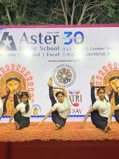 My students performing a seated leg-hold pose during a Navratri festival, blending cultural celebration with yogic art.