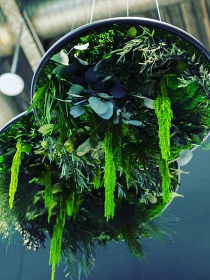 A custom-designed hanging sculpture filled with artificial greenery. This unique, multi-layered piece acts as a central lighting feature and a suspended garden in one.