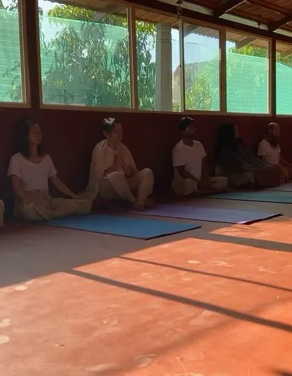 Students sit in meditation, bathed in the long shadows of the afternoon sun. The shala is a space of deep peace and introspection.