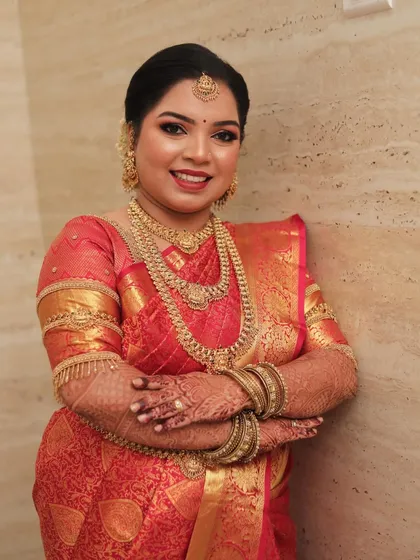A smiling portrait of the bride, her traditional gold jewelry perfectly complementing her makeup.