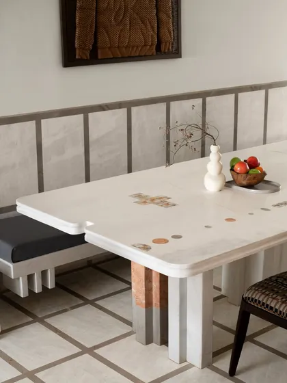 This dining space is a study in geometry and craft. The custom dining table is made of solid stone, with playful, colourful marble inlays. It is paired with a sculpted stone bench, turning everyday meals into a design-led ritual.