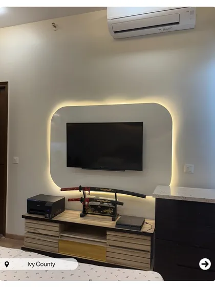 A unique bedroom TV unit with a custom backlit panel that creates a soft glow. The samurai sword display adds a personal and striking touch to the space.