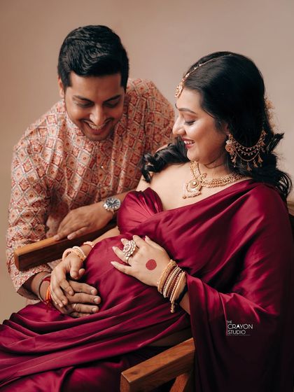 The shared joy between partners is a beautiful part of the maternity story. Here, his happy gaze meets hers as they both gently hold the baby bump, a moment of shared anticipation.
