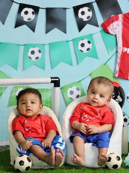 Twin brothers ready for their football debut. This half-birthday shoot is perfectly coordinated, right down to the jerseys and the soccer balls at their feet.