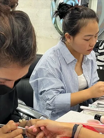 A bustling nail art class, with students focused on their work, learning from trainers and each other.