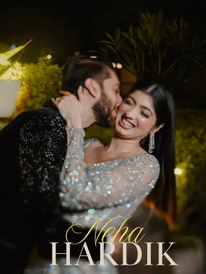 A candid and romantic moment from a cocktail party. The groom steals a kiss on the cheek, and the bride's joyful laugh is perfectly captured.