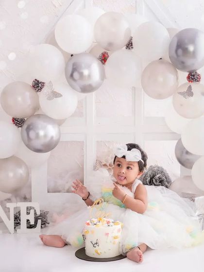 The birthday girl sits with her pretty cake in our all-white "One" setup, a serene and beautiful way to capture this milestone.