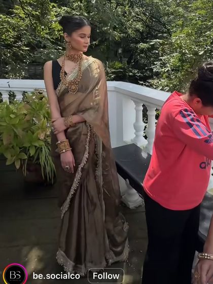 A behind-the-scenes shot of a model in the olive green organza saree during a photoshoot.