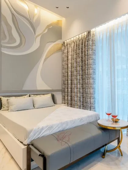 This bedroom is a beautiful example of serene elegance. The focal point is the artistic, abstract headboard panel, which adds a soft, flowing element to the room. The neutral color palette and clean lines create a calming retreat.