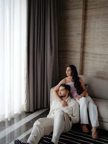 A quiet, candid moment indoors. The couple relaxes together by a window, sharing a peaceful embrace that speaks volumes about their comfort and connection with each other.