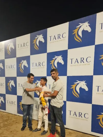 Celebrating success. Our riders are presented with their awards in front of the TARC Equestrian Centre banner.