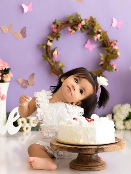 A curious glance towards the cake during a lavender and butterfly themed first birthday session.