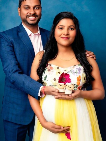A sweet family portrait with the parents-to-be holding tiny teddy bears, wearing our yellow and white floral gown.