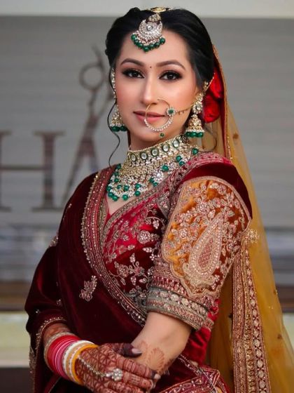 A bride in a rich velvet lehenga. The makeup is defined and elegant, with a smokey eye and a neutral lip to balance the heavy outfit and jewelry.