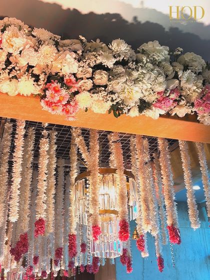 The top of the floral canopy, showing the dense arrangement of flowers and a chandelier, creating a rich and opulent look.