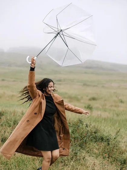 Embracing the unpredictable weather in Meghalaya. A clear umbrella becomes a fun prop, adding a touch of whimsy to this shot of the bride-to-be dancing in the open fields, showcasing her free spirit.