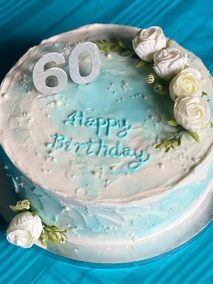 A simple yet elegant cake to celebrate a 60th birthday. The design features a soft blue watercolor effect on buttercream, delicate white roses, and a sparkling "60" to mark the special milestone.