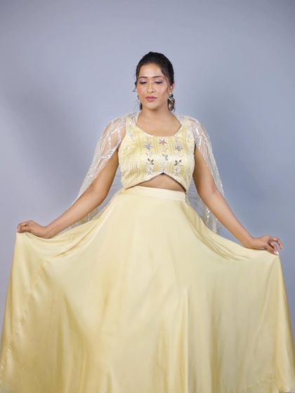 A full view of the pastel yellow lehenga, showing the elegant fall of the satin skirt and the delicate, shimmering cape. This outfit is designed to be light, comfortable, and effortlessly chic.