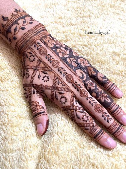 The reverse side of a contemporary bridal design, showing a mix of patterns on the back of the hand. It combines a floral net, geometric fills, and a leafy wristband.