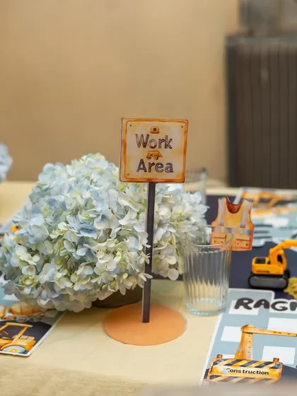 "Work Area" signs and floral centerpieces made of blue hydrangeas and yellow mums continue the construction theme down the length of the table.