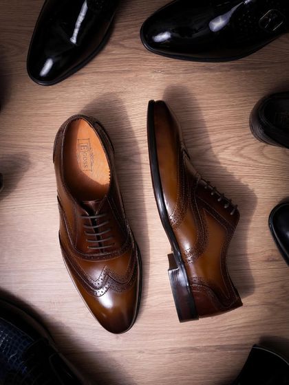 Different angles of these polished brown leather shoes, laid out on a wooden floor. This shot is perfect for showing product details from multiple perspectives.
