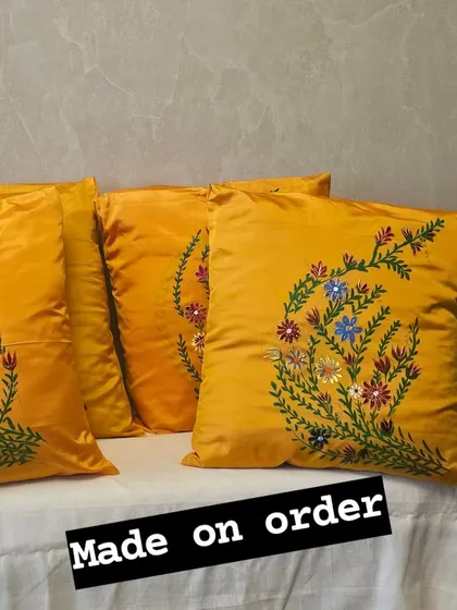 Brighten up your home with these custom-made silk cushion covers. This set of four vibrant yellow pillows features a delicate, hand-painted floral design, perfect for adding a touch of elegance and personality to any living space.