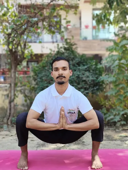 An instructor demonstrates Malasana (Garland Pose). This squatting pose aids digestion, strengthens the ankles and back, and tones the abdominal muscles.