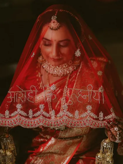 A Punjabi bride in her stunning red saree and customized veil, a beautiful detail from her wedding to her Odia groom. This portrait captures her serene beauty in the moments before the ceremony.