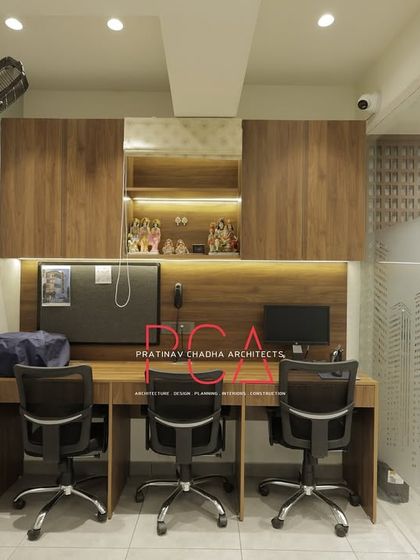 A shared workstation designed for functionality and warmth, featuring wood-laminate cabinetry with integrated lighting and a small niche for religious idols, personalizing the corporate space.