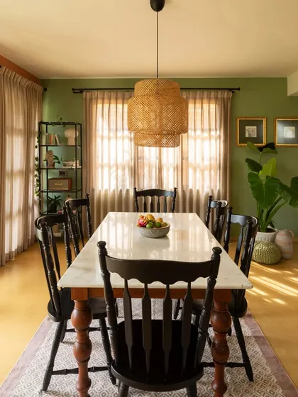 The dining room at Casa 503 is designed to be a warm, inviting space for family meals. The golden light from the large windows, combined with the olive green walls and classic wooden furniture, creates a perfect setting for making memories.