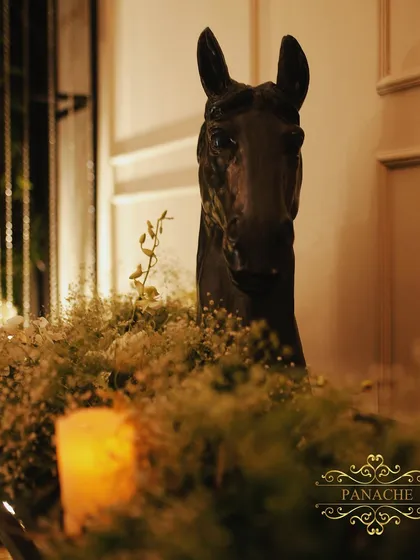 A moody, artistic shot of a horse-head sculpture, surrounded by the soft glow of candles and delicate baby's breath.