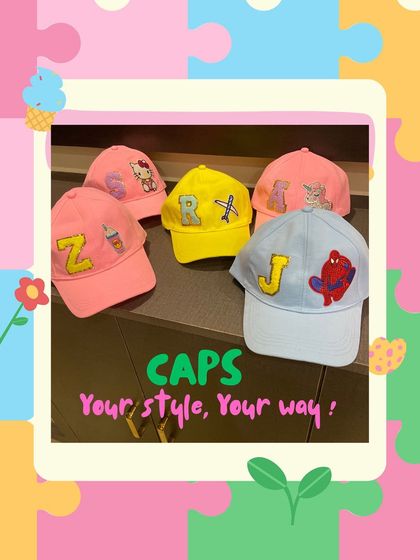 A colorful arrangement of five custom kids' caps, each with a unique initial and character patch, including Hello Kitty and Nemo. This shows the wide variety of design possibilities.