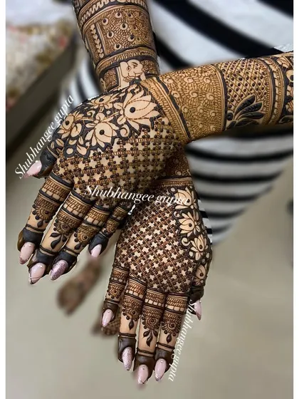 A close-up of a floral back-of-hand design. The delicate flowers and jaal pattern create a beautiful texture, perfect for a bridal look.