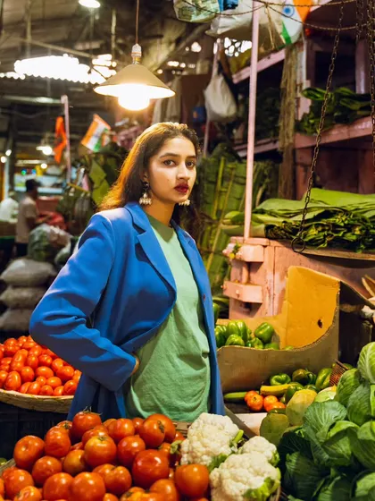This shot uses the market's own lighting to create a dramatic effect, highlighting the model's pose and the rich colors of the vegetables.