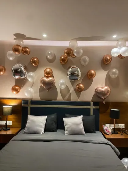 A close-up of the balloon arrangement over the headboard. This shows the detail in the placement of the rose gold, white, and unique silver disco ball style balloons for a fun yet elegant birthday decoration.