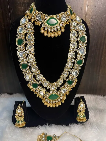 A clear product view of the green Kundan bridal set on a display bust. You can see the quality of the stones and the two distinct necklaces that create a perfect layered look.