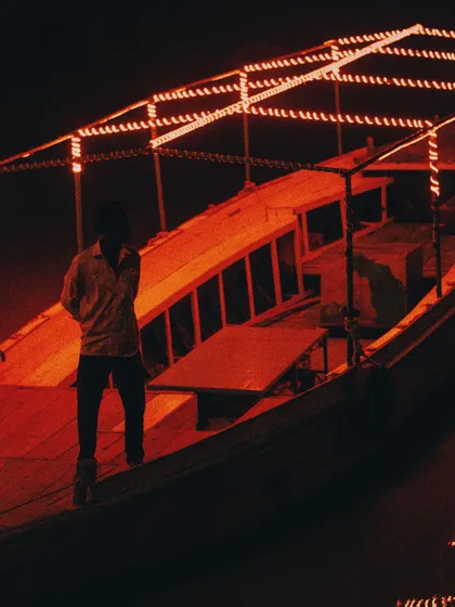 a boat on the ghats illuminated by red lights at night. the use of a single, bold color in a dark environment is a powerful tool for drawing user attention in ui design.