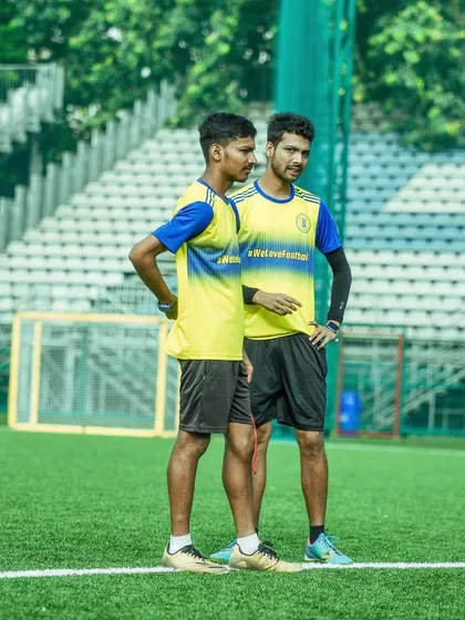 Two of our coaches stand on the sideline, engaged in a discussion during a training session. This photo represents the care, passion, and dedication that defines the Bravo coaching team.