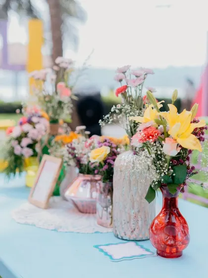 A close-up of a table centerpiece with a variety of colorful flowers in different glass vases. This simple yet beautiful arrangement adds a touch of charm to the event.