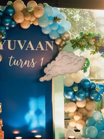 A magnificent royal blue theme for a first birthday, featuring a carousel horse, cloud cutouts, and a grand balloon arch in shades of blue, white, and silver.