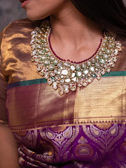 A close-up of the stunning polki and pearl necklace against the rich purple silk, a combination that exudes luxury.
