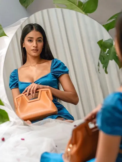 A reflection shot for the Sarjaa campaign, with the model looking into a round mirror. The composition is intimate, focusing on the connection between the person and the accessory.