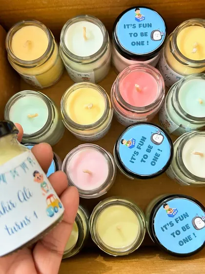 A closer look at the birthday return gift candles. We used a mix of pastel colors for the wax, and the labels say 'It's fun to be one!'.