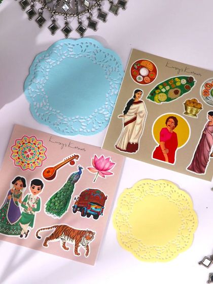 Colorful sticker sheets and doilies from the Indian Aesthetics kit, featuring traditional Indian figures and symbols.