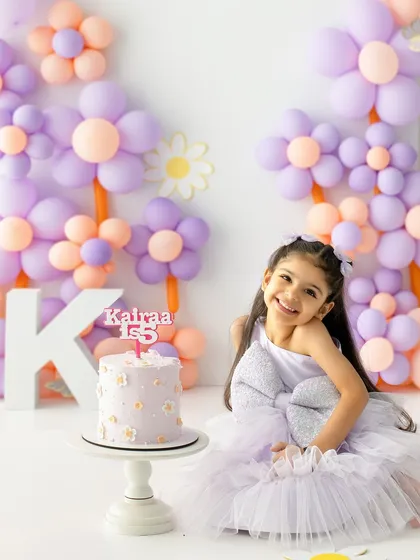 A huge smile for the birthday girl. This shot captures the pure, simple happiness of celebrating a milestone with a special cake and a fun outfit.